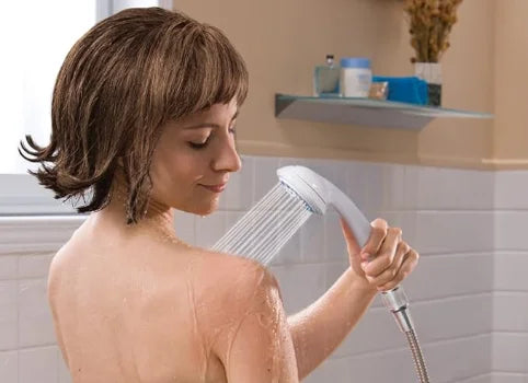 Woman using a handheld shower head in a bathroom setting