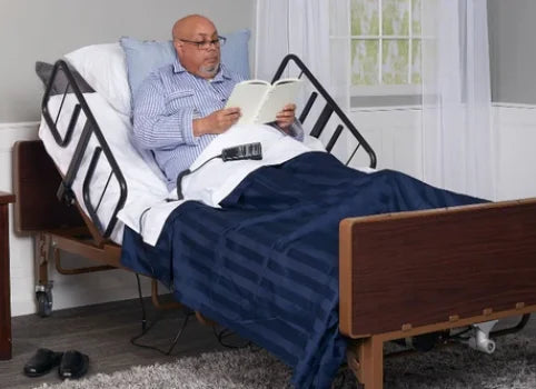 Man reading a book in a hospital bed with a blue blanket