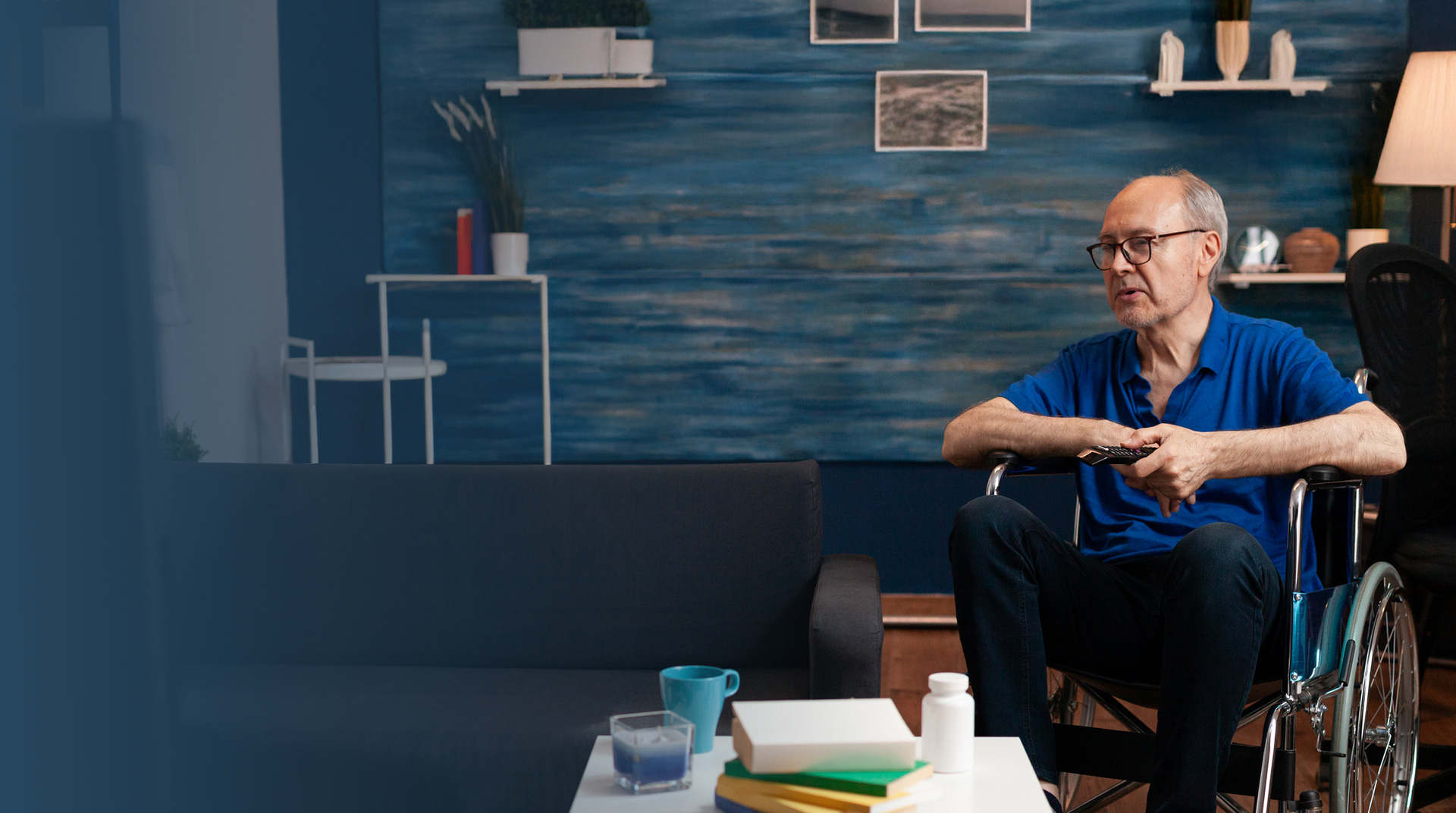 Man in a wheelchair sitting in a room with blue walls and various items on shelves.