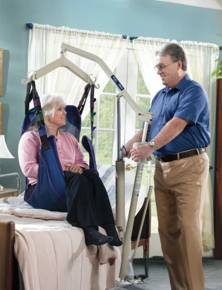 Person using a medical lift to assist another person in a home setting.